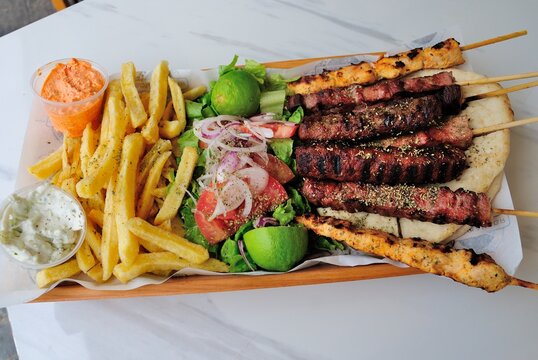 Cypriot style mixed souvlaki and gyros plate with fries, dips, fresh salad and lime served on a pita bread in Cyprus