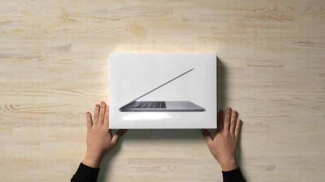 Top-down view of a customer receiving a brand new, in box laptop.