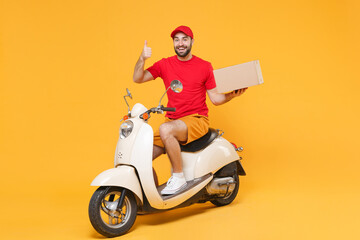 Delivery man in red cap tshirt uniform driving moped motorbike scooter hold cardboard box isolated...