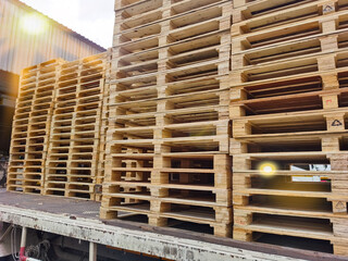 Worker driving forklift truck to unload wooden pallets stack from truck to the cargo warehouse to support shipment for logistics and transportation industry 