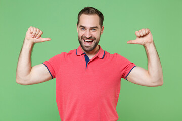 Fototapeta premium Funny young bearded man guy in casual red pink t-shirt posing isolated on green background studio portrait. People sincere emotions lifestyle concept. Mock up copy space. Pointing thumbs on himself.