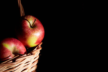Braided basket with red apples on a black background