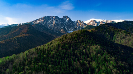 Aerial view of green hills and mountains covered with snow in summer or spring. Giewont mountain massif in the Tatra Mountains of Poland and panorama of Zakopane