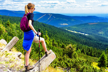 Adventurous girl on the edge of a hiking trail overlooking the beautiful Krkonose (Sudets) in Czech Republic during a vibrant summer. - obrazy, fototapety, plakaty