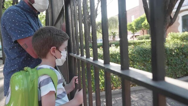 Child And Parent With Mask Looking Through School Gate