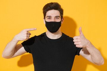 Young man guy in black t-shirt isolated on yellow background. Epidemic pandemic spreading...