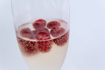 Glass of fresh cold champagne with red raspberry inside on white background summer party cocktail concept 
