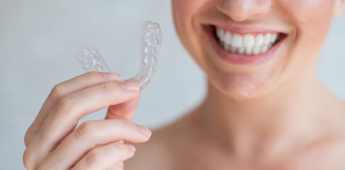 Close-up of orthodontic silicone transparent teeth aligner in female hands. Unrecognizable woman...