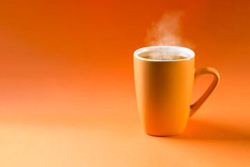 Orange ceramic cup with tea on an orange background