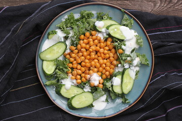 Healthy vegetarian salad with roasted chickpeas,kale, cucumber and dressing. Healthy detox eating. Vegan and vegetarian food.