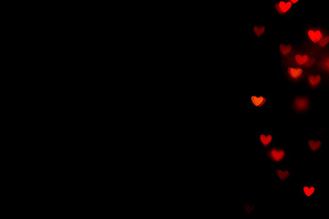 Little red bokeh hearts on black background. For Valentine's Day celebrations