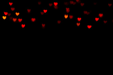 Fototapeta na wymiar Little red bokeh hearts on black background. For Valentine's Day celebrations