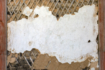 Background texture of old plaster on the wall with remnants of white paint, primer and wooden substrate.. Copy Space.