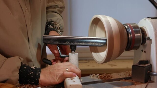 Craftsman works with workpiece in authentic workshop. Woodworker handles wood by bench. Making beautiful wooden handmade dish. Creation of unusual plate. Carpenter cuts wood by graver in soft focus