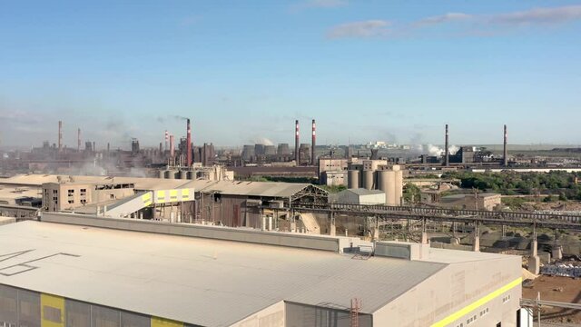 Industrial area in russian ural region, drone zoom in. Aerial shot of garages, industrial plants, factory tubes on the horizon under grey cloudy sky