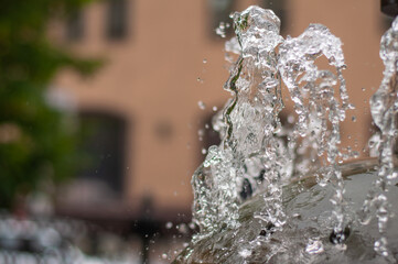 Naklejka na ściany i meble Water gurgling from a street fountain. A splash of water in a fountain, an abstract image.