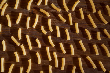 Fototapeta premium a lot of Yellow pasta lies on a brown table. Close-up. Top view.