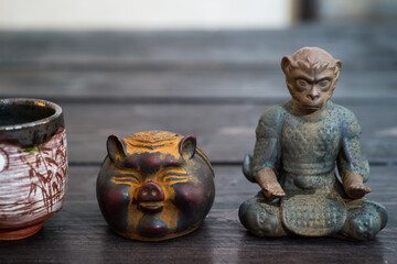 Different tea decorative chinese figurines: king of monkey, pig and tea bowl on dark wooden table