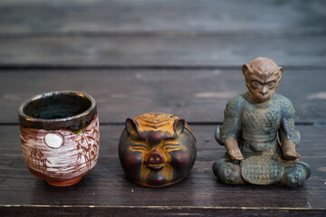 Different tea decorative chinese figurines: king of monkey, pig and tea bowl on dark wooden table