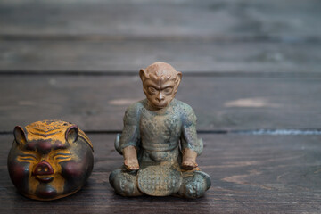 Different tea decorative chinese figurines: king of monkey and pig on dark wooden table