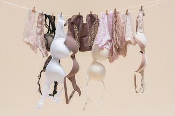 Female underwear is hanging on the rope on light background. - obrazy, fototapety, plakaty