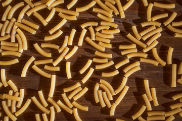 Yellow pasta lies on a brown table. Close-up.