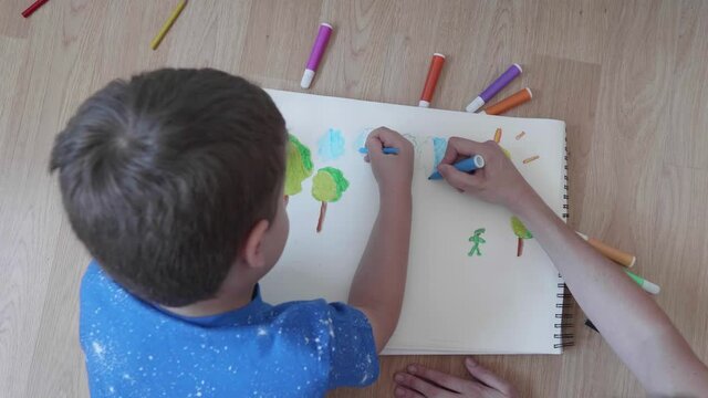 Boy drawing with his mother on the floor