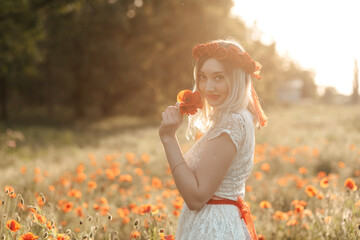 Obraz premium Summer girl in poppy field holding a poppies bouquet.