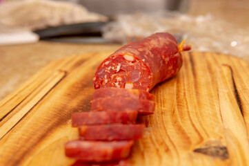 Close up view of a fresh sliced salami  placed on top of a wooden cutting board. Taken under a soft white light.