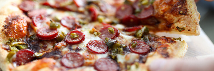 Male hand holding big piece of tasty fresh pizza