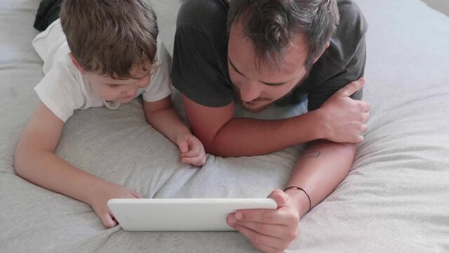 Child and parent watching the tablet lying