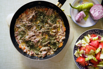 Fresh mushroom saute with bacon and vegetables, decorated with salad on a kitchen table, top view 