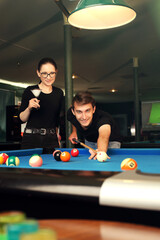 Billiard club, social event at a billiard tournament, playing billiards. A woman and a man are playing pool in the club