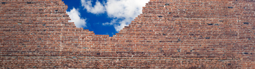 image of a destroyed brick wall and sky with clouds
