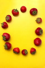 Juicy summer red strawberries on a yellow background. Fresh and healthy fruit from the market.