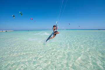 kiter does a difficult trick on a background of transparent water and blue sky