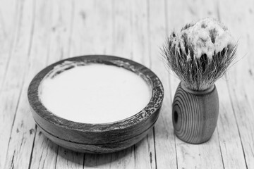 bnw picture of a wooden bowl of shaving soap and a brush
