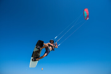 Plakat kiter does a difficult trick on a background of transparent water and blue sky