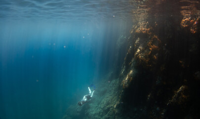 Naklejka na ściany i meble Young man swimming and freediving in the blue clear mediterranean sea