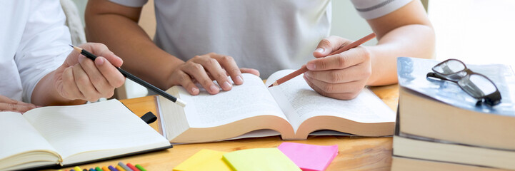 Two students or classmates helps friend do homeworks learning in classroom