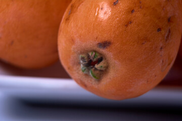 Two medlars on white plate