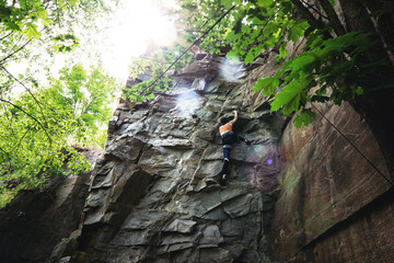 Climber extreme girl climbs a rock on a top rope. Summer of 2020, Buky canyon in Ukraine