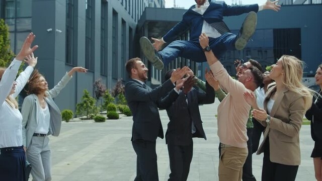 Satisfied group of co-workers celebrating fun party outdoor. Several business men throwing their friend in the air having funny hangout. Celebration. Success.
