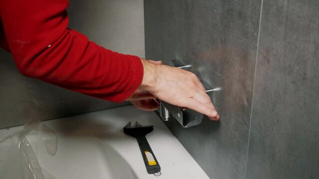 The plumber installs the shower faucet in the bathroom.