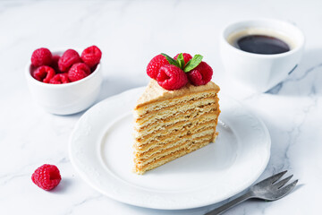 Honey cake with caramel cream filling decorated with strawberries and mint leaves
