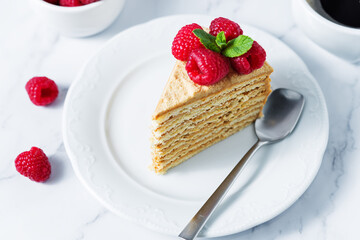 Honey cake with caramel cream filling decorated with strawberries and mint leaves