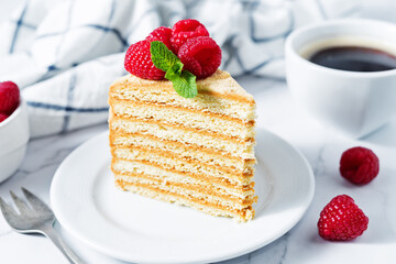 Honey cake with caramel cream filling decorated with strawberries and mint leaves