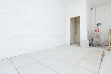 Floor tile installation, worker in a white office room