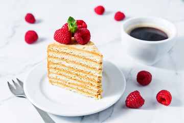 Honey cake with caramel cream filling decorated with strawberries and mint leaves