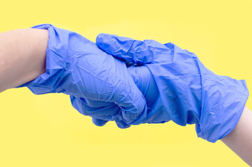 Hands of two people in blue sterile gloves say Hello. The concept of protection from viruses. Selective focus.